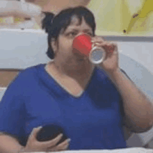 a woman is drinking from a red cup while holding a cup .