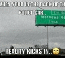 a green highway sign that says `` when your in the back of the police car , reality kicks in ''