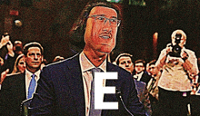 a man in a suit and tie stands in front of a microphone with the letter e on his face