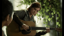 a woman is playing an acoustic guitar in a video game while another woman watches .