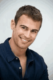 a young man wearing a blue shirt is smiling for the camera .