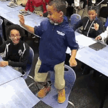 a boy with blood on his face is standing on a chair in front of a group of people .