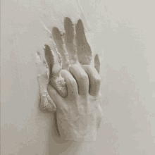 a white statue of a hand is hanging on a white wall