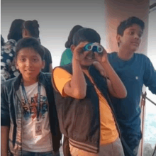 a group of young boys are looking through binoculars .