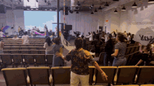 a group of people are dancing in an auditorium with a wall that says " the presence transforming us "