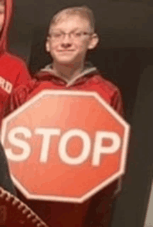 a boy is holding a stop sign in his hand .