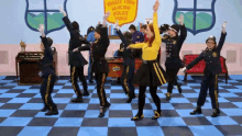 a group of people are dancing in front of a sign that says wiggle town dancing police