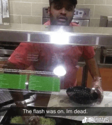 a man in a red shirt is standing in front of a display case with the words the flash was on im dead