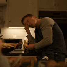 a man sitting at a kitchen counter eating a banana and wearing a shirt that says ' nyc ' on it