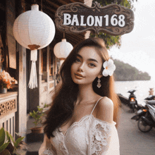 a woman with a flower in her hair stands in front of a sign that says balon168