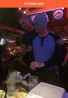 two men are hugging in a restaurant with a sign that says 9 years ago