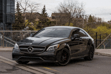 a black mercedes is parked on the side of a road