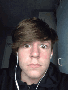 a young man wearing headphones makes a funny face with his eyes wide open