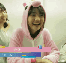 a girl wearing a pink unicorn hooded sweatshirt is smiling