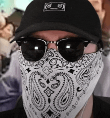 a man wearing sunglasses and a bandana has a ray-ban hat on his head