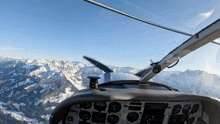 a cockpit of an airplane flying over a snowy mountain landscape