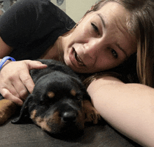 a woman laying on a couch with a puppy that has a blue bracelet that says rescue