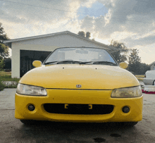 a yellow honda car is parked in front of a house