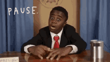 a young boy in a suit and tie is sitting at a desk in front of a sign that says president .