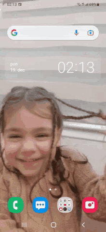 a little girl is smiling on the screen of a phone