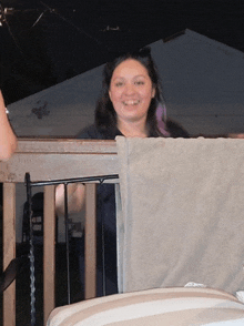 a woman sitting on a balcony with a towel hanging on the railing