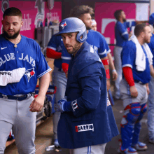 a man wearing a blue jays jersey is standing in the dugout