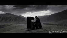 a black and white photo of a man playing a piano with mountains in the background and the name qauran elm on the bottom right