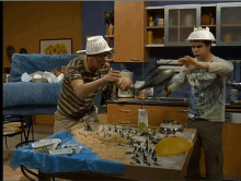 two men wearing paper hats are playing with toys on a table in a kitchen