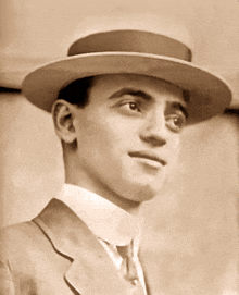 a man wearing a hat and a suit looks to his left