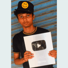 a young man wearing a smiley face hat holds up a youtube award