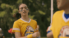 a woman in a yellow shirt with a horse on it is standing next to a man in a yellow jersey .