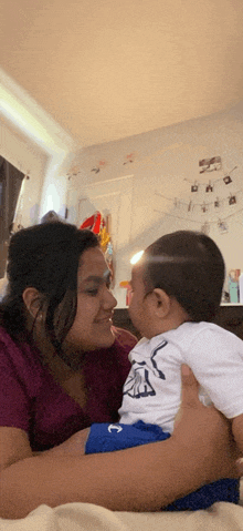 a woman is holding a baby in her arms and the baby is wearing a shirt that says ' a ' on it