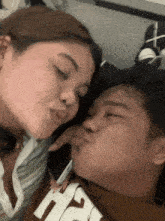 a woman is kissing a man on the cheek while they are laying on the floor .