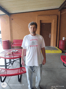 a man standing in front of a picnic table wearing a shirt that says keeping it news