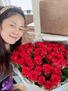 a woman holding a heart shaped bouquet of red roses with the number b612 in the corner