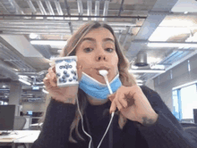 a woman wearing a mask is holding a container of yogurt with blueberries on it