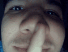 a close up of a person 's face with their finger in their nose