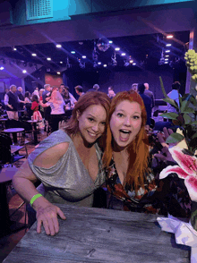 two women are posing for a picture in front of a stage