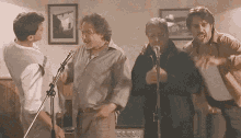 three men singing into microphones in a room