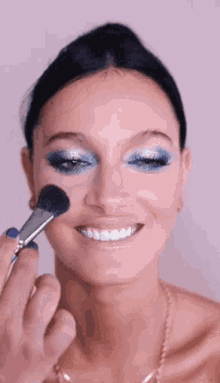 a woman is smiling while getting her makeup done .