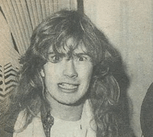 a black and white photo of a woman with long curly hair making a funny face .