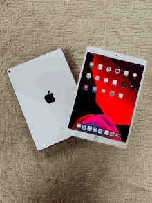 a white apple ipad sits on a carpet next to another ipad