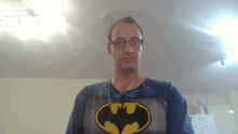 a man wearing glasses and a blue shirt with a batman logo on it