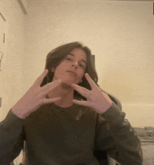 a young man making a peace sign with his hands in front of his face