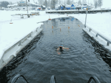 a person in a green swim cap is swimming in a frozen river