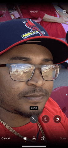 a man wearing a cardinals hat and glasses is being photographed