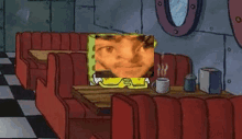 spongebob squarepants is sitting at a table in a diner with a picture of him on it .