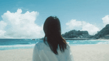 a woman is standing on a beach looking out over the ocean