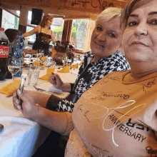 two women sitting at a table with a coca cola bottle in the background