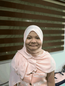 a young girl wearing a hijab and a pink shirt